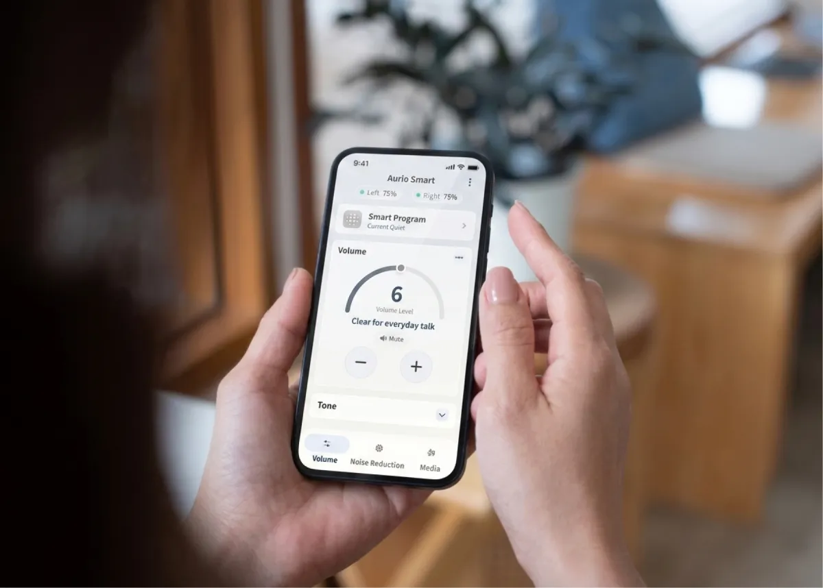 A hand holding a phone running the Aurio app, on the volume screen set for everyday talk